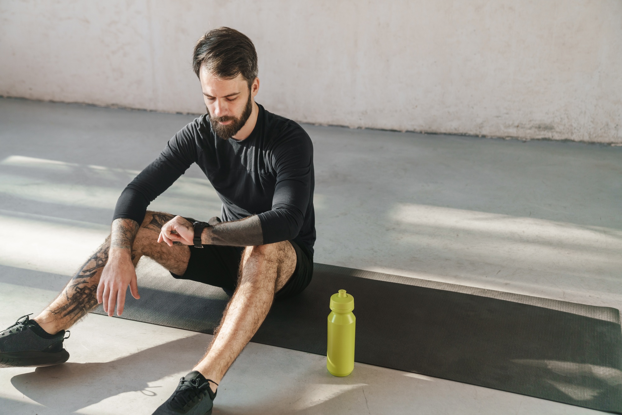 Young brunette bearded sportsman sitting